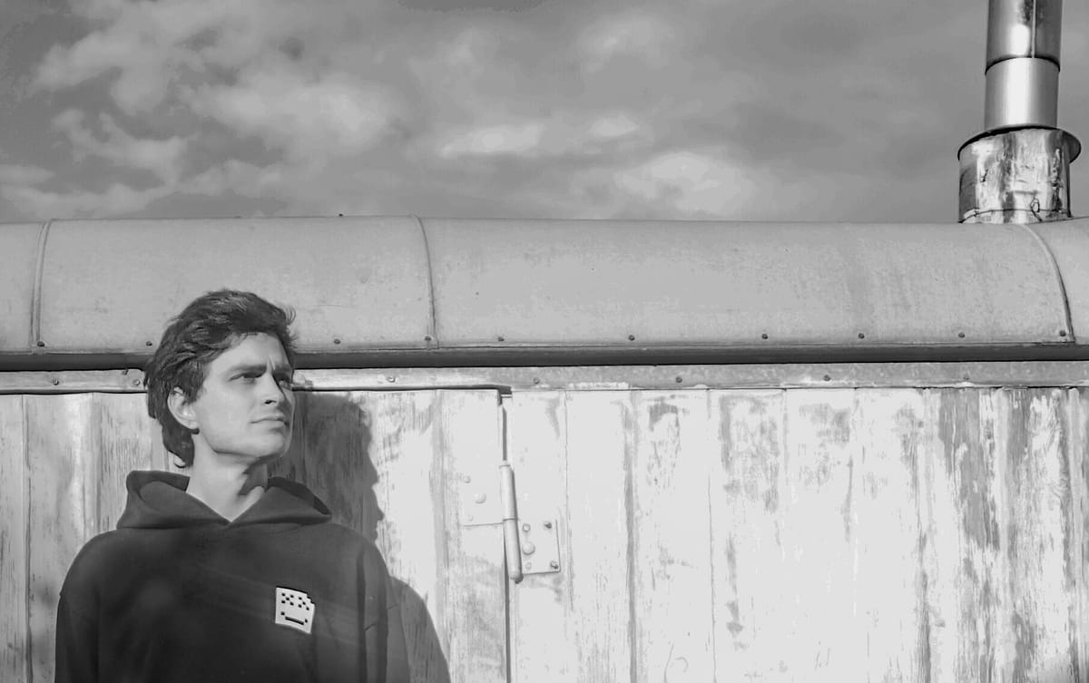 A black and white photo of Rain standing in front of a trailer, looking up toward the sky.